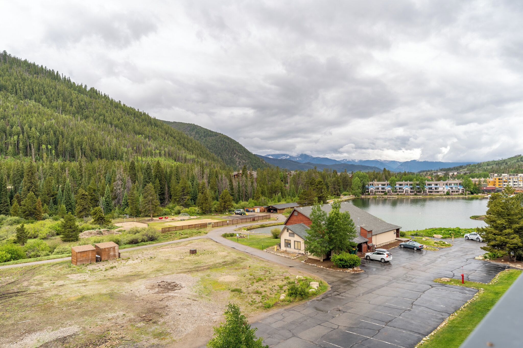 Ett hotell med en parkeringsplats, en liten byggnad och en sjö.