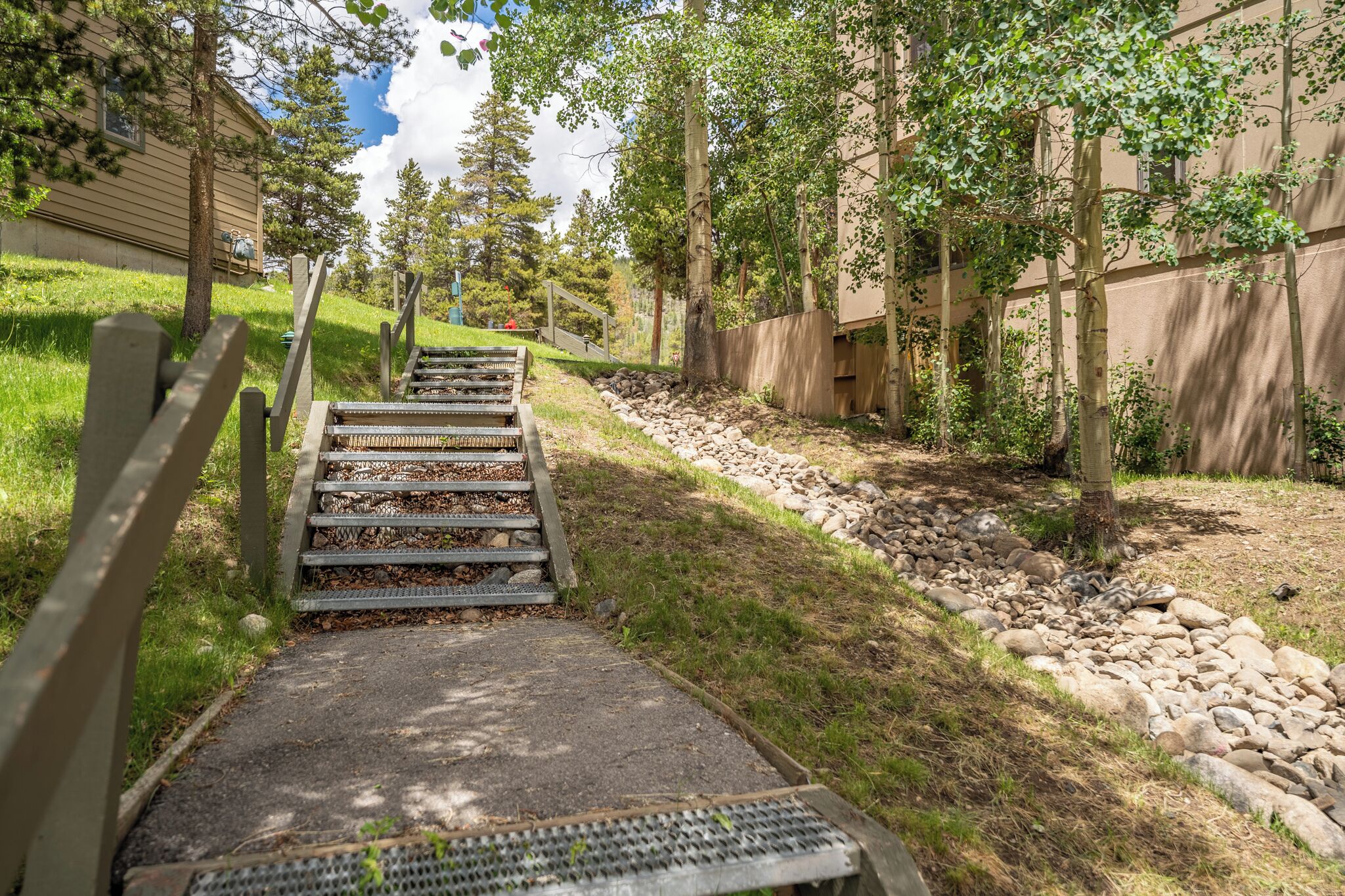 A pathway leading to a building with a wooden fence on one side and a grassy area on the other.