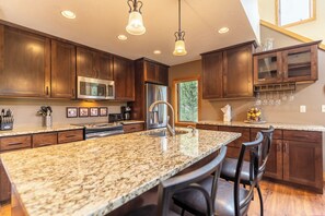 Una cocina moderna con encimeras de granito, electrodomésticos de acero inoxidable y armarios de madera oscura.