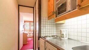 A narrow kitchen with a dishwasher, a coffee maker, and a microwave. - Bright studio with balcony at the foot of Plagne Centre slopes (La Plagne)