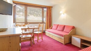 A room with a wooden desk, a red sofa, a small cabinet, and a window with curtains. - Bright studio with balcony at the foot of Plagne Centre slopes (La Plagne)