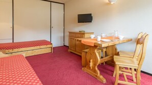 A room with a bed, a wooden desk with a chair, a television, and a cabinet. - Bright studio with balcony at the foot of Plagne Centre slopes (La Plagne)