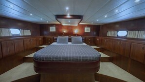 A spacious bedroom with a large bed, wooden cabinetry, and a central light fixture.