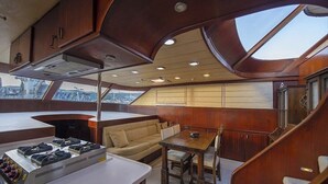 A yacht's interior with a dining area, a sofa, and a kitchen with a stove.