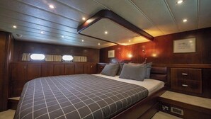 A spacious cabin with a large bed, wooden paneling, and built-in storage.