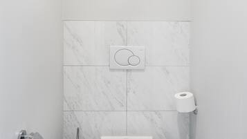 Une salle de bain moderne équipée de toilettes, d’un bidet et d’une poubelle.