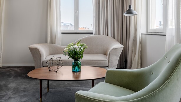Une pièce avec deux canapés, une table basse et un vase rempli de fleurs.