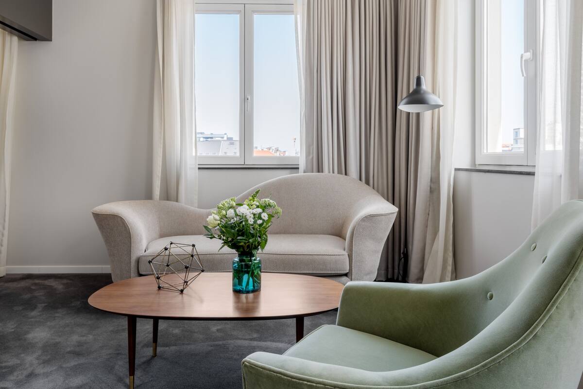 A room with two sofas, a coffee table, and a vase with flowers.
