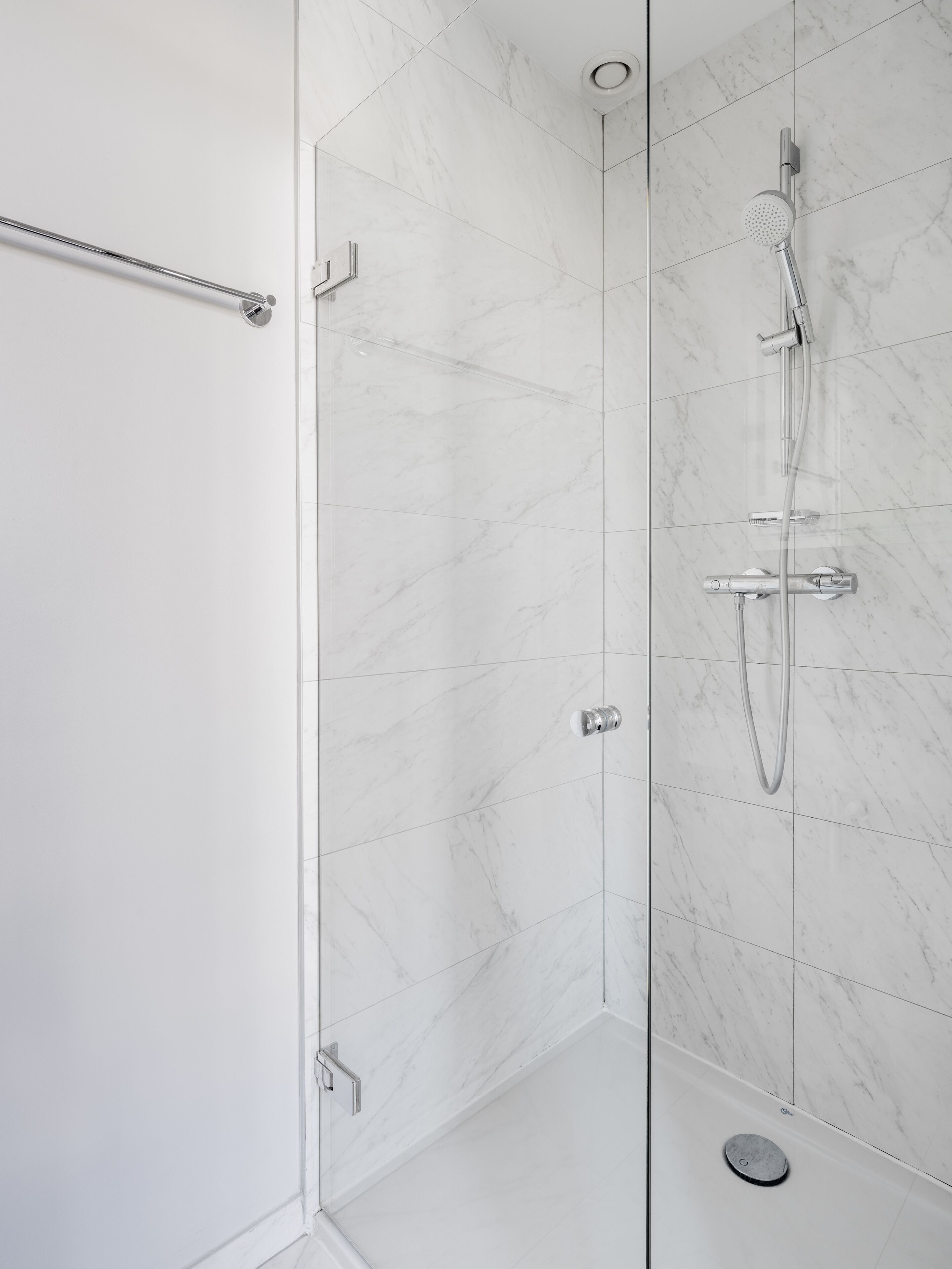A modern shower with a handheld showerhead and a wall-mounted faucet.