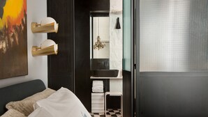 Una habitación de hotel con cama, un escritorio pequeño, un espejo y una ventana con persianas.