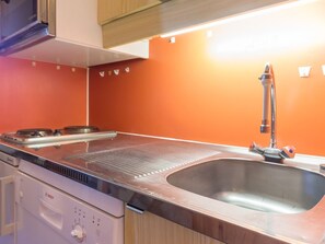 A kitchen with a stainless steel stove, a sink, and wooden cabinets.
