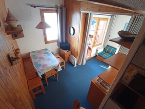 A compact room with a table, chairs, a television, and a window.