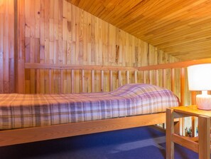 A wooden bunk bed with a plaid bedspread and a bedside table with a lamp. - Cozy Mezzanine Apartment · Ski-In/Ski-Out · Sleeps 5 · Balcony (Plagne Villages)