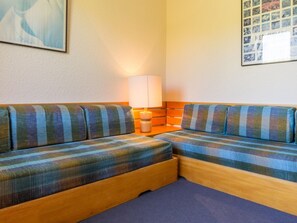 A room with a sofa set against a wall, a lamp, and a framed picture. - Cozy Mezzanine Apartment · Ski-In/Ski-Out · Sleeps 5 · Balcony (Plagne Villages)