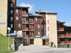 A multi-story hotel with wooden balconies and a stone facade. - Cozy Mezzanine Apartment · Ski-In/Ski-Out · Sleeps 5 · Balcony (Plagne Villages)