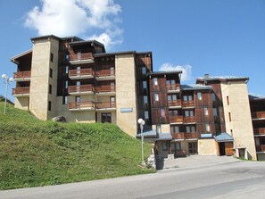 A multi-story hotel with balconies and a stone facade. - Cozy Mezzanine Apartment · Ski-In/Ski-Out · Sleeps 5 · Balcony (Plagne Villages)