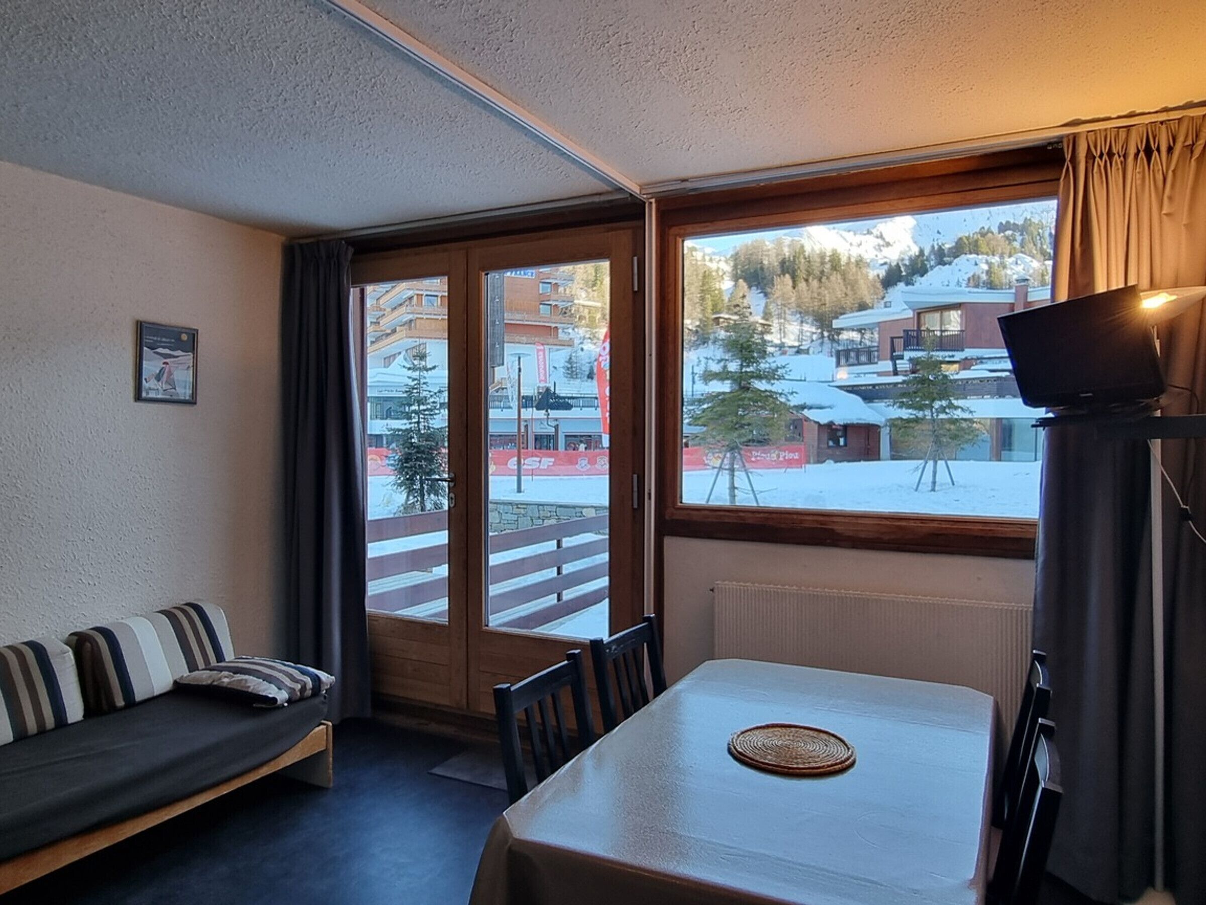 Une pièce avec un canapé, une table et une vue sur un espace extérieur enneigé.