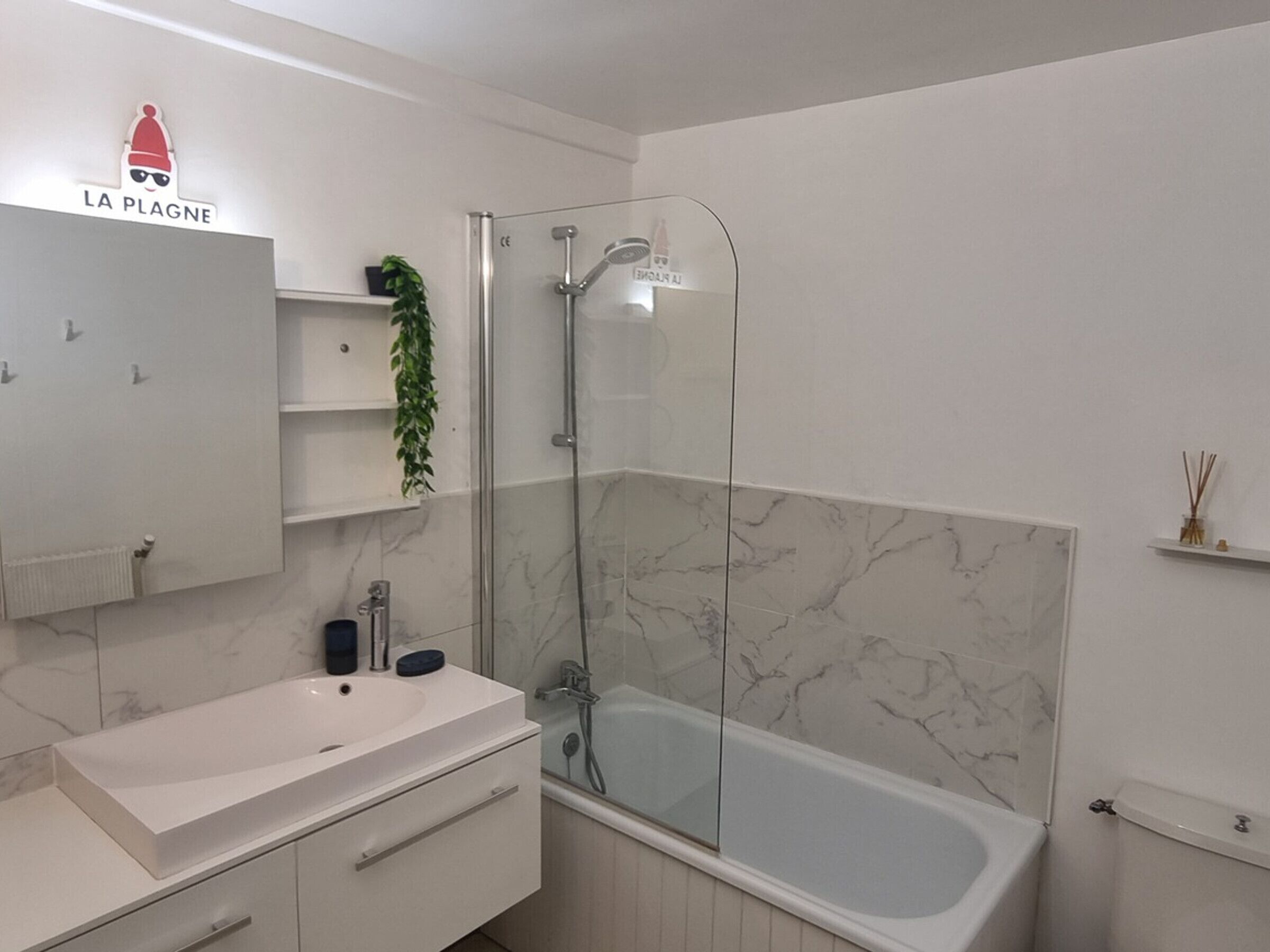 A modern bathroom with a glass-enclosed shower, a white sink, and a bathtub.