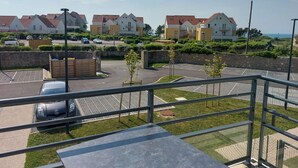 A residential area with houses, a parking lot, and a view of the sea.