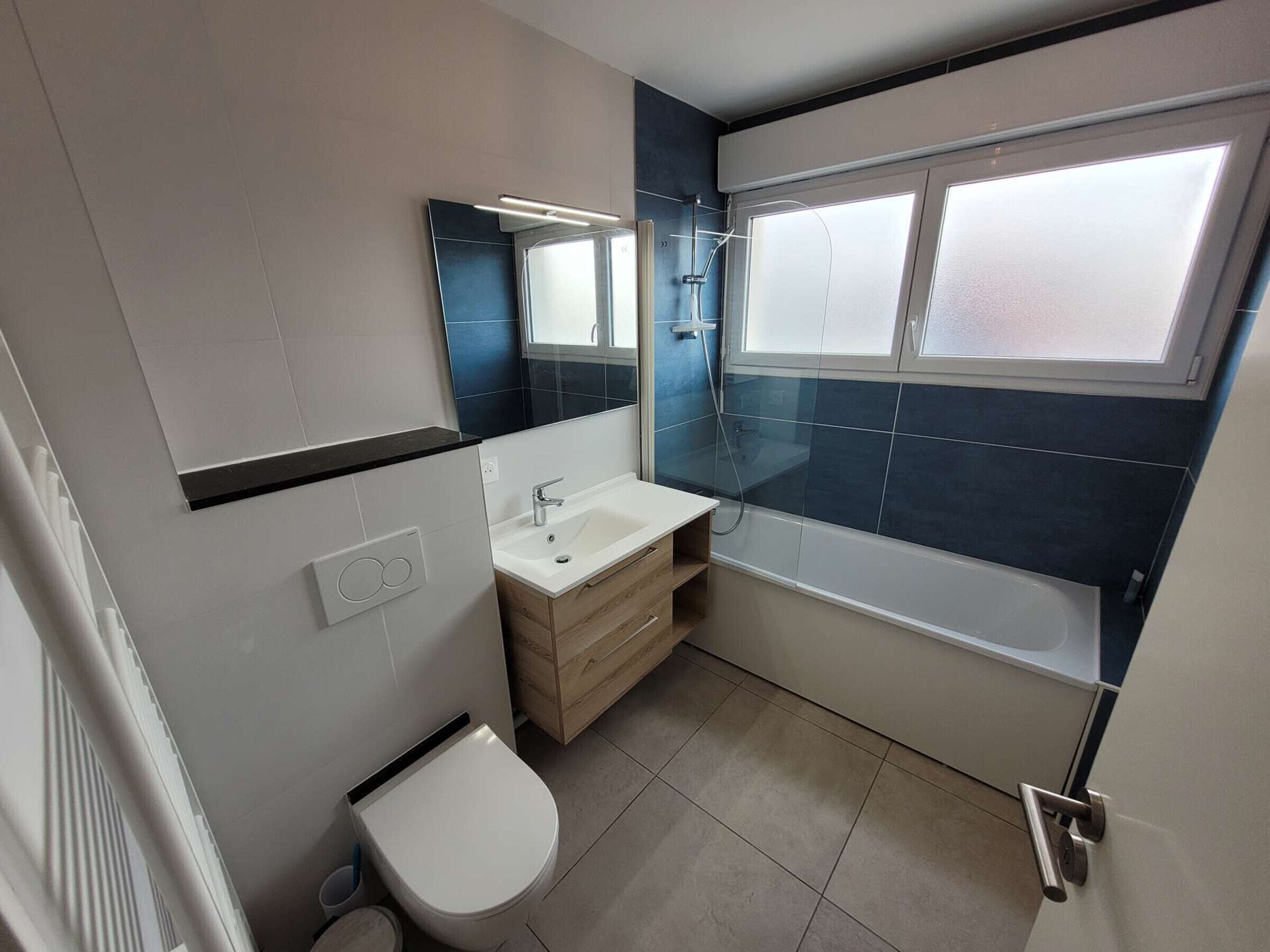Ein modernes Badezimmer mit Toilette, Waschbecken, Waschtisch und Badewanne.