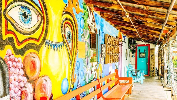 Un banco de madera y un mural colorido con diseños abstractos.