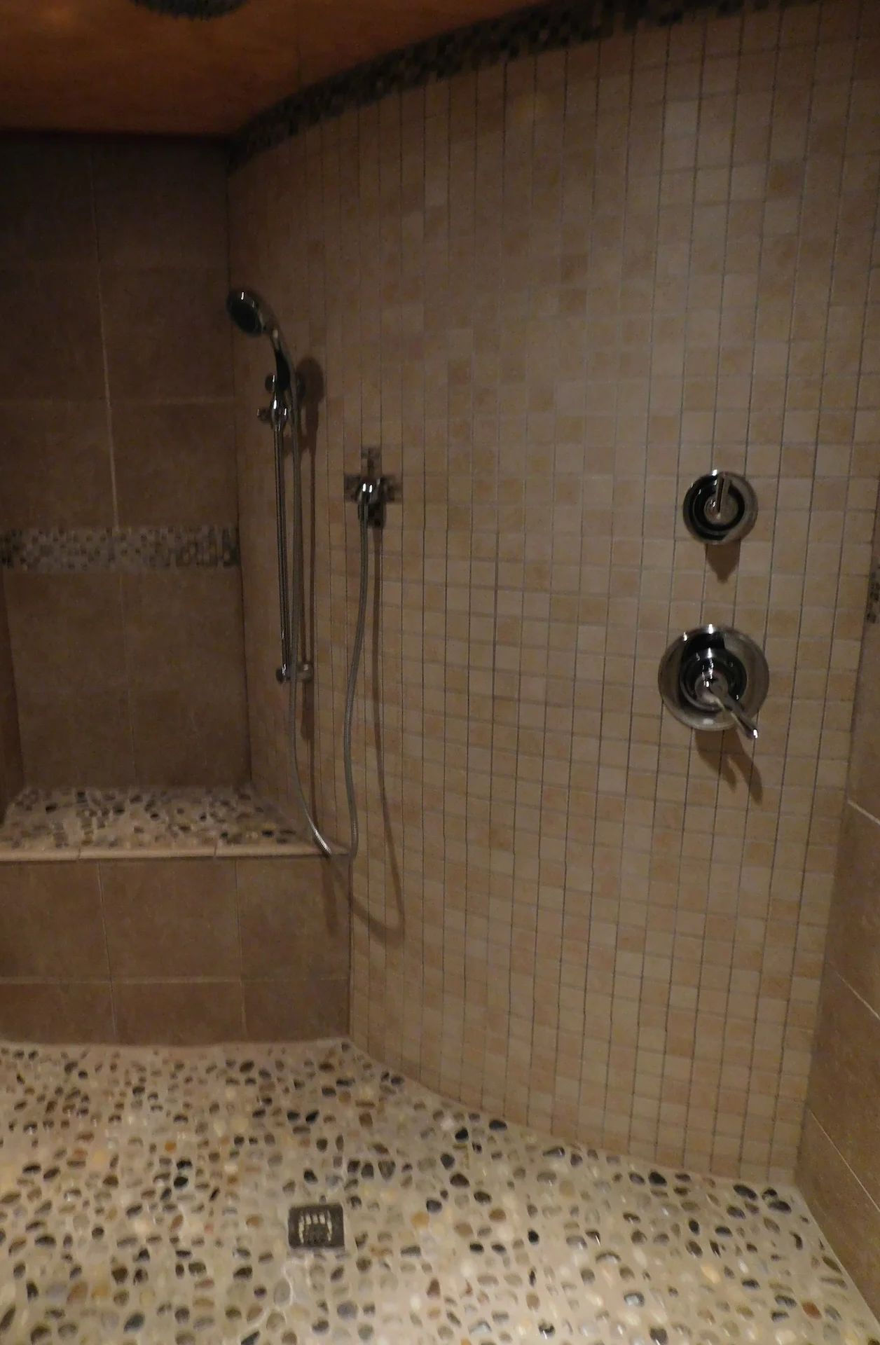 A shower area with tiled walls, a bench, and a showerhead.