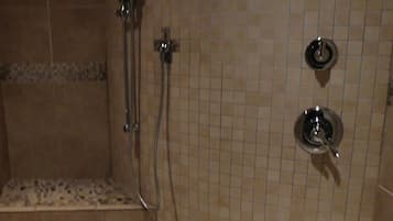 A shower area with tiled walls, a bench, and a showerhead.
