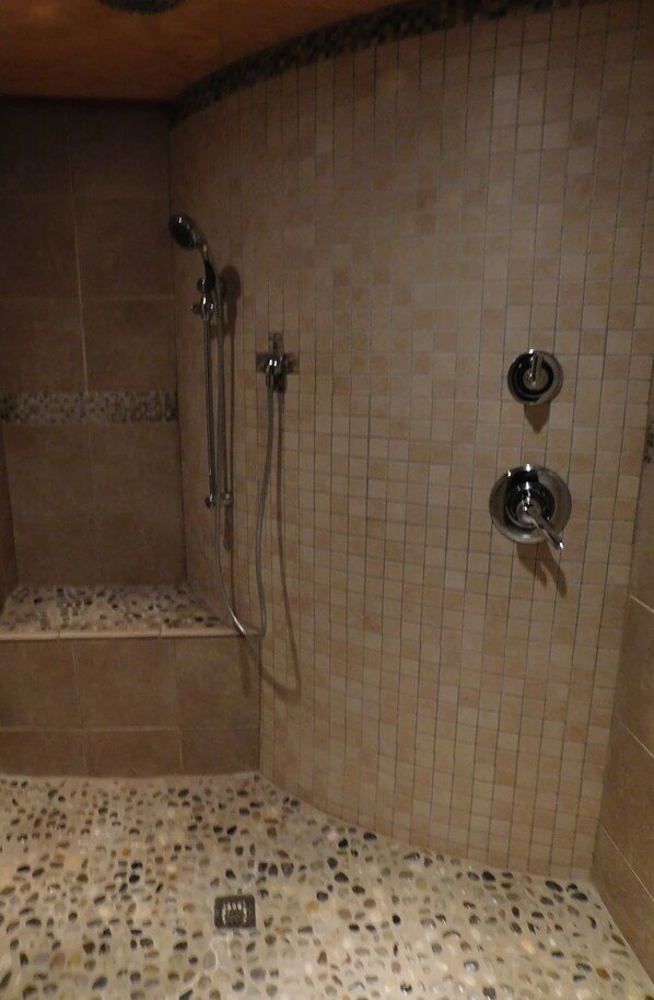 A shower area with tiled walls, a bench, and a showerhead.