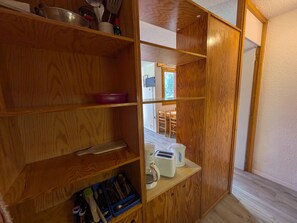 A wooden kitchen cabinet with shelves containing kitchen utensils, a toaster, and a coffee maker. - Functional Studio for 4 · Ski-in/Ski-out at Plagne Villages (Plagne Villages)