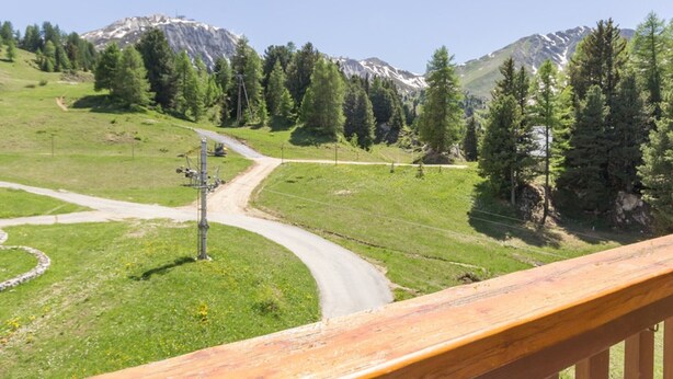 A scenic mountain landscape with a winding road, a wooden deck, and a power line. - Functional Studio for 4 · Ski-in/Ski-out at Plagne Villages (Plagne Villages)