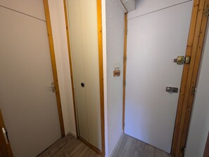 A hallway with two doors, one with a wooden frame and the other with a metal handle.