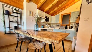 A kitchen with a wooden table and chairs, white cabinets, and a hanging plant.