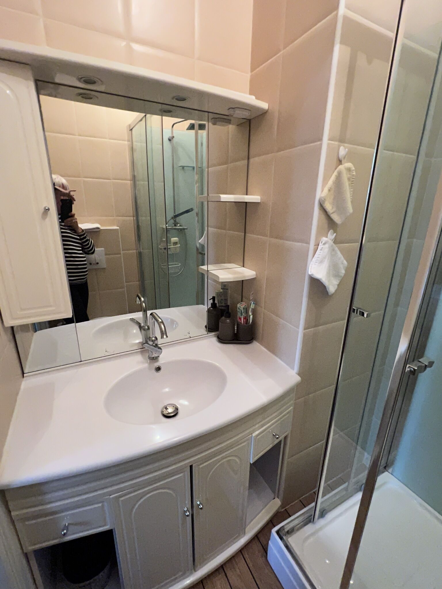 Un bagno moderno con lavandino bianco, uno specchio grande e un box doccia in vetro.