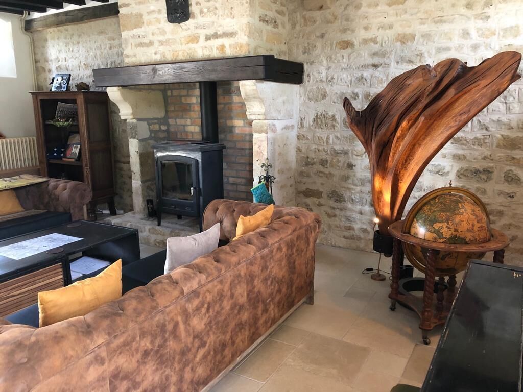 Una sala de estar acogedora con pared de piedra, chimenea, una gran escultura de madera y un globo terráqueo sobre un atril.