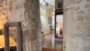 Un intérieur rustique avec des murs en briques apparentes, un escalier en bois et un miroir qui reflète une partie de la pièce.