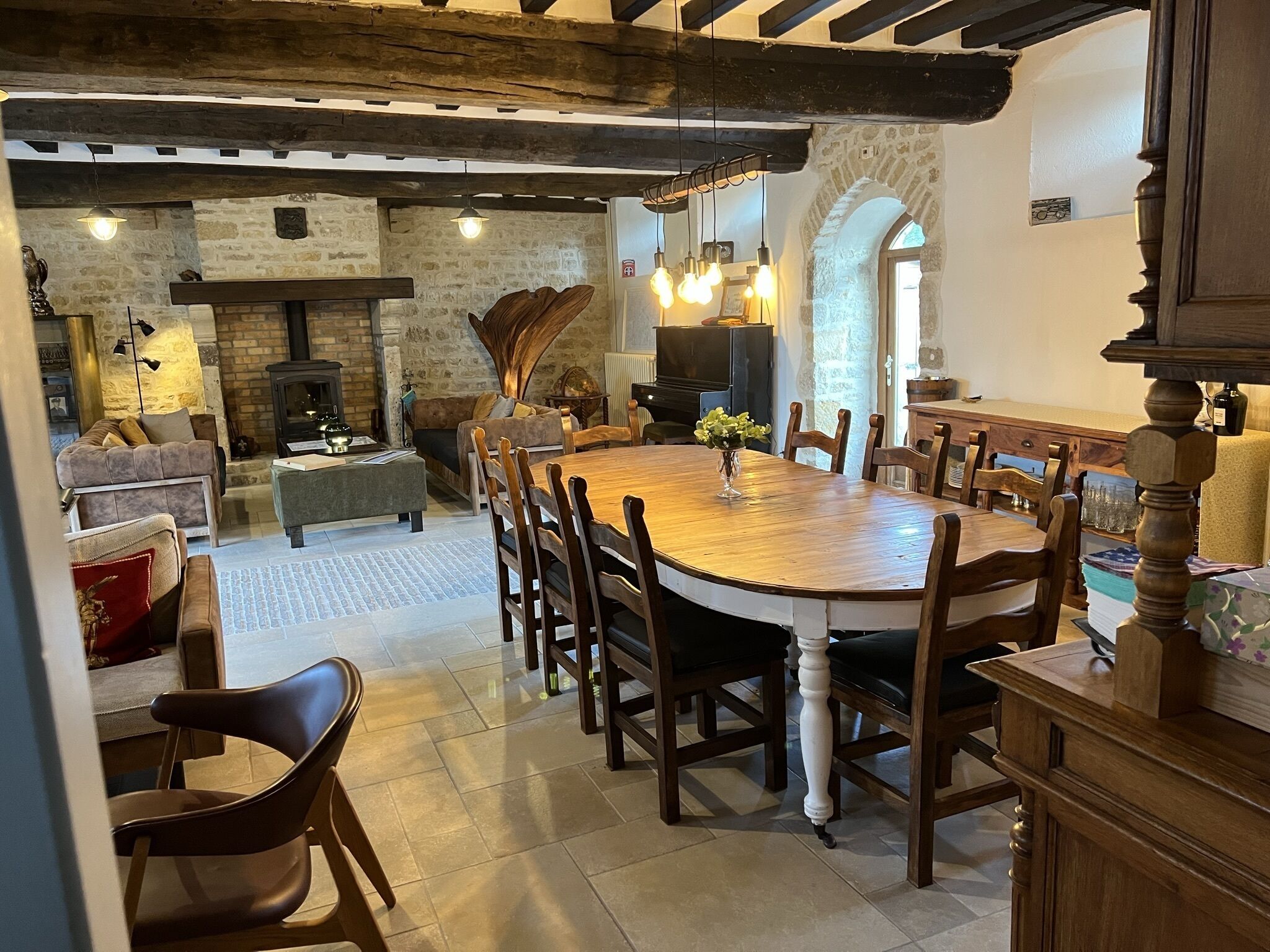 A cozy dining area with a wooden table and chairs, a fireplace, and stone walls.