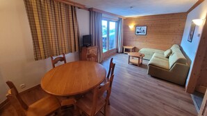 Une pièce chaleureuse avec une table à manger en bois, des chaises, un canapé et un téléviseur.