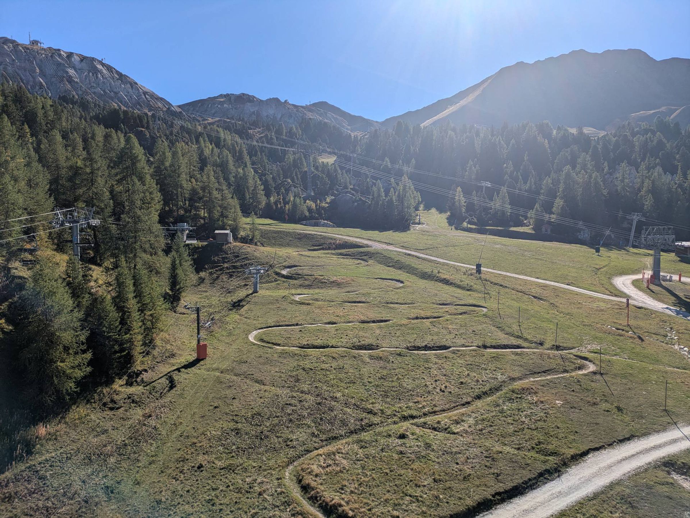 Eine Berglandschaft mit einem gewundenen Pfad, Stromleitungen und blauem Himmel.