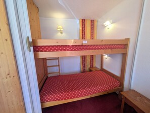 A bunk bed with a ladder, a small table, and two wall-mounted lights.