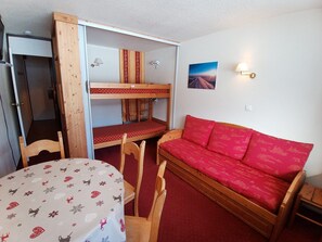 A room with bunk beds, a sofa, a table, and chairs.