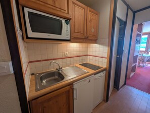 A compact kitchen with a microwave, sink, and dishwasher.