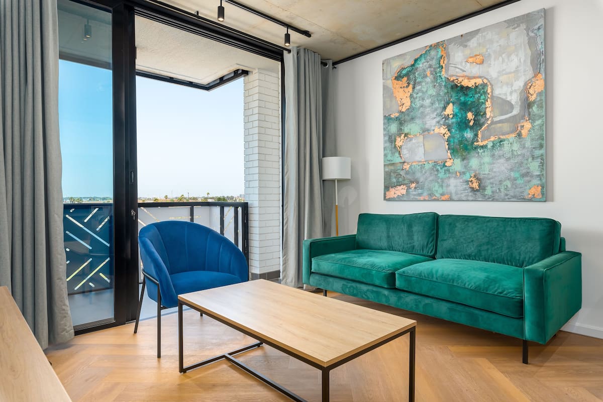 A modern living room with a green sofa, a blue chair, and a wooden coffee table.