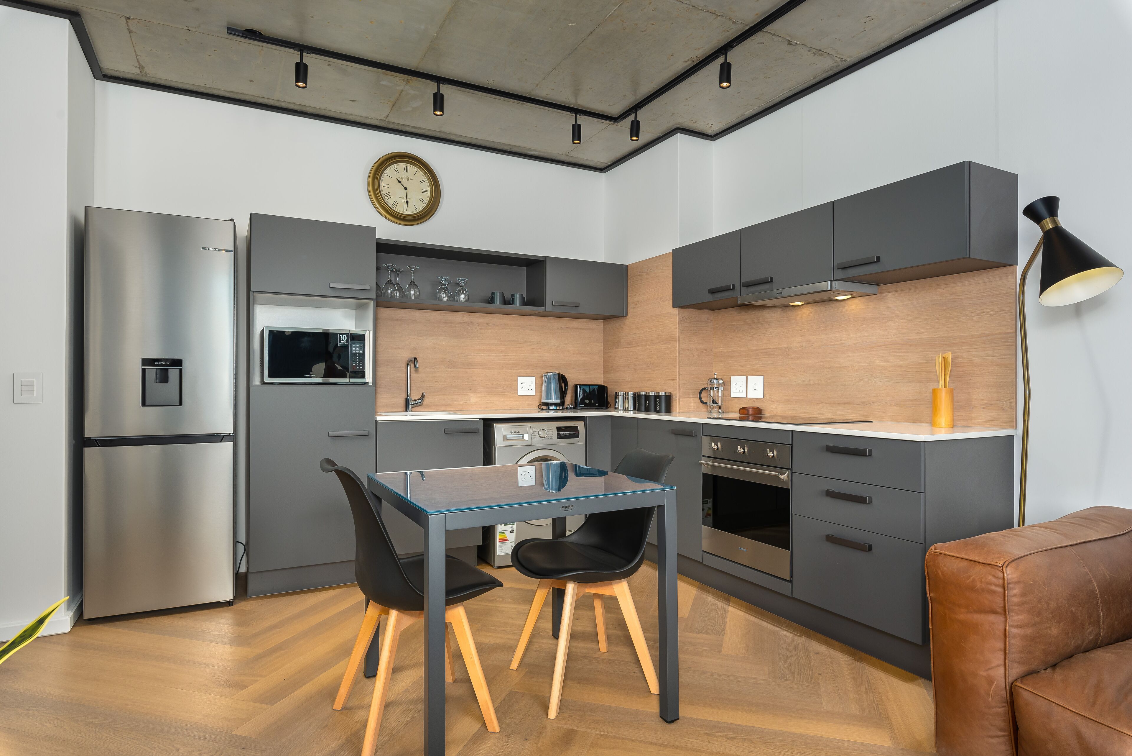 A modern kitchen with a dining table, chairs, and a clock on the wall.