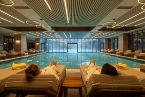 A large indoor swimming pool with lounge chairs and towels, surrounded by large windows. - Megasaray Mount Erciyes (Kayseri)