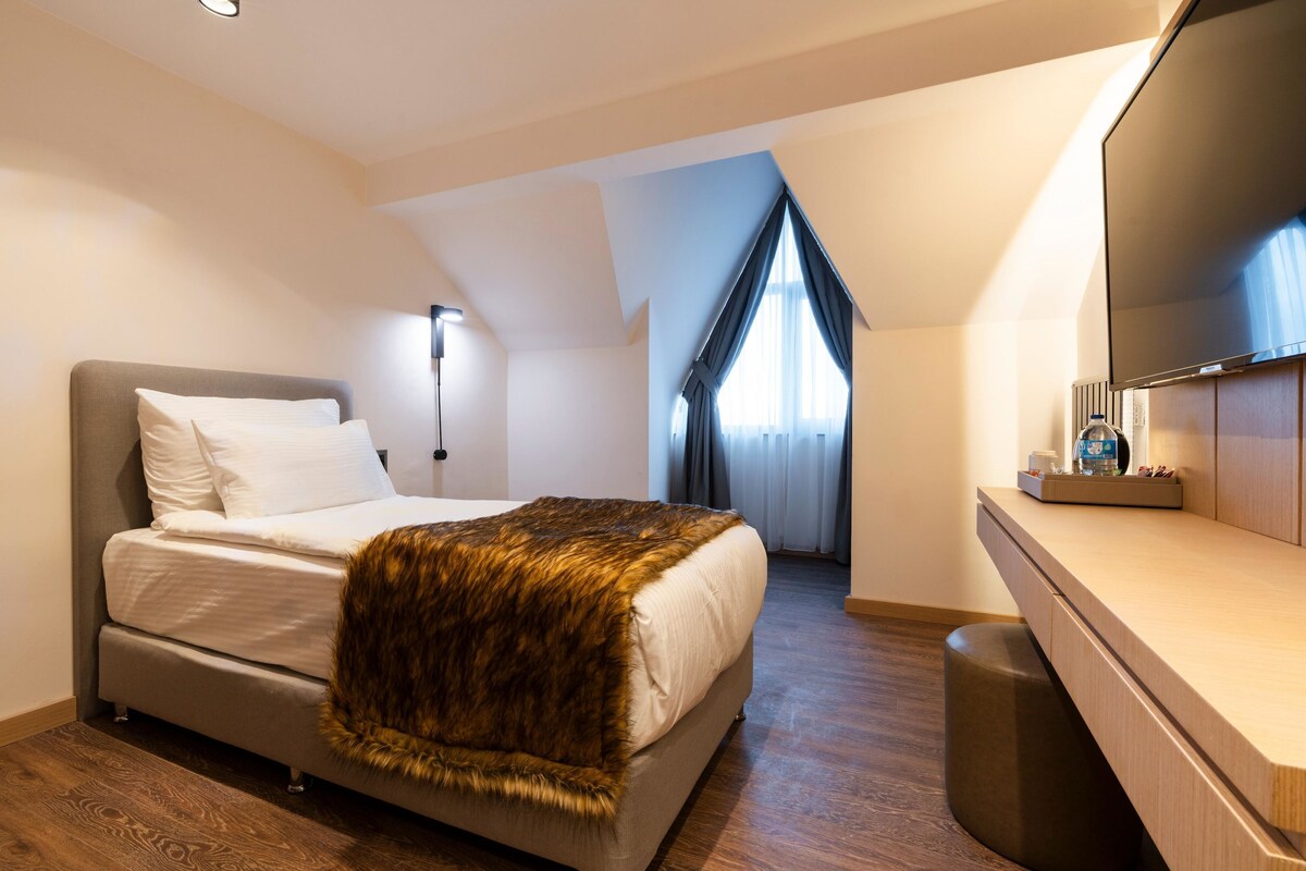 Een moderne slaapkamer met een groot bed, een houten vloer, een spiegel en een televisie.