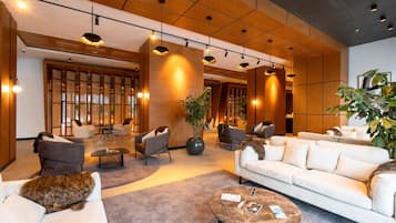 A spacious lobby with modern furniture, a large plant, and a cat resting on a couch.
