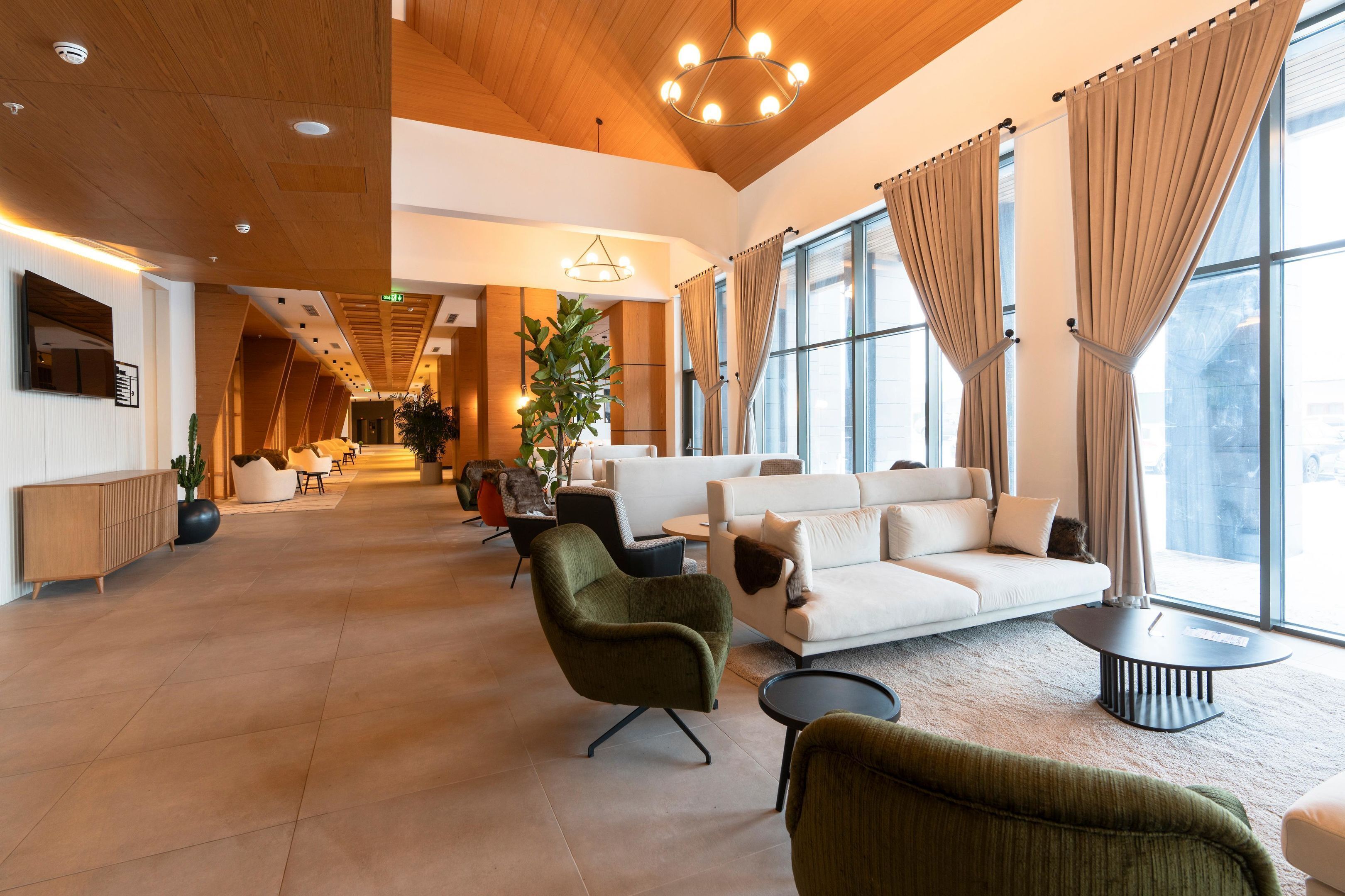 A spacious lobby with a modern design, featuring a large sofa, armchairs, and a coffee table.