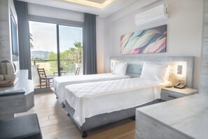Une chambre d’hôtel avec deux lits, un balcon donnant sur un beau paysage, un tableau accroché au mur et un téléphone sur la table de chevet.