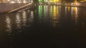 Eine Flusslandschaft bei Nacht, mit Gebäuden links und einer Brücke in der Mitte.