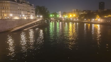 Eine Flusslandschaft bei Nacht, mit Gebäuden links und einer Brücke in der Mitte.